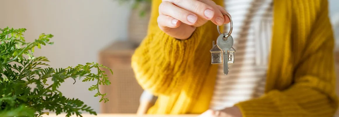 Person hält Schlüssel mit Haus-Anhänger